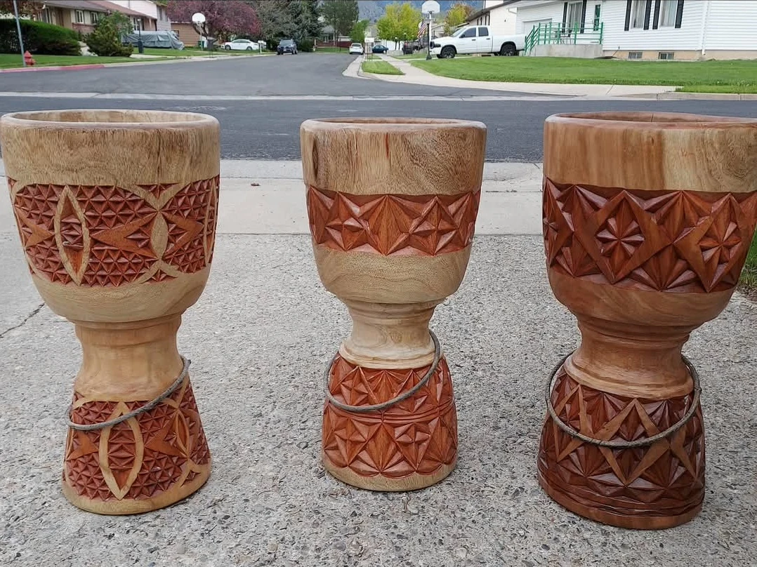 Three unfinished djembe shells showing different carved patterns