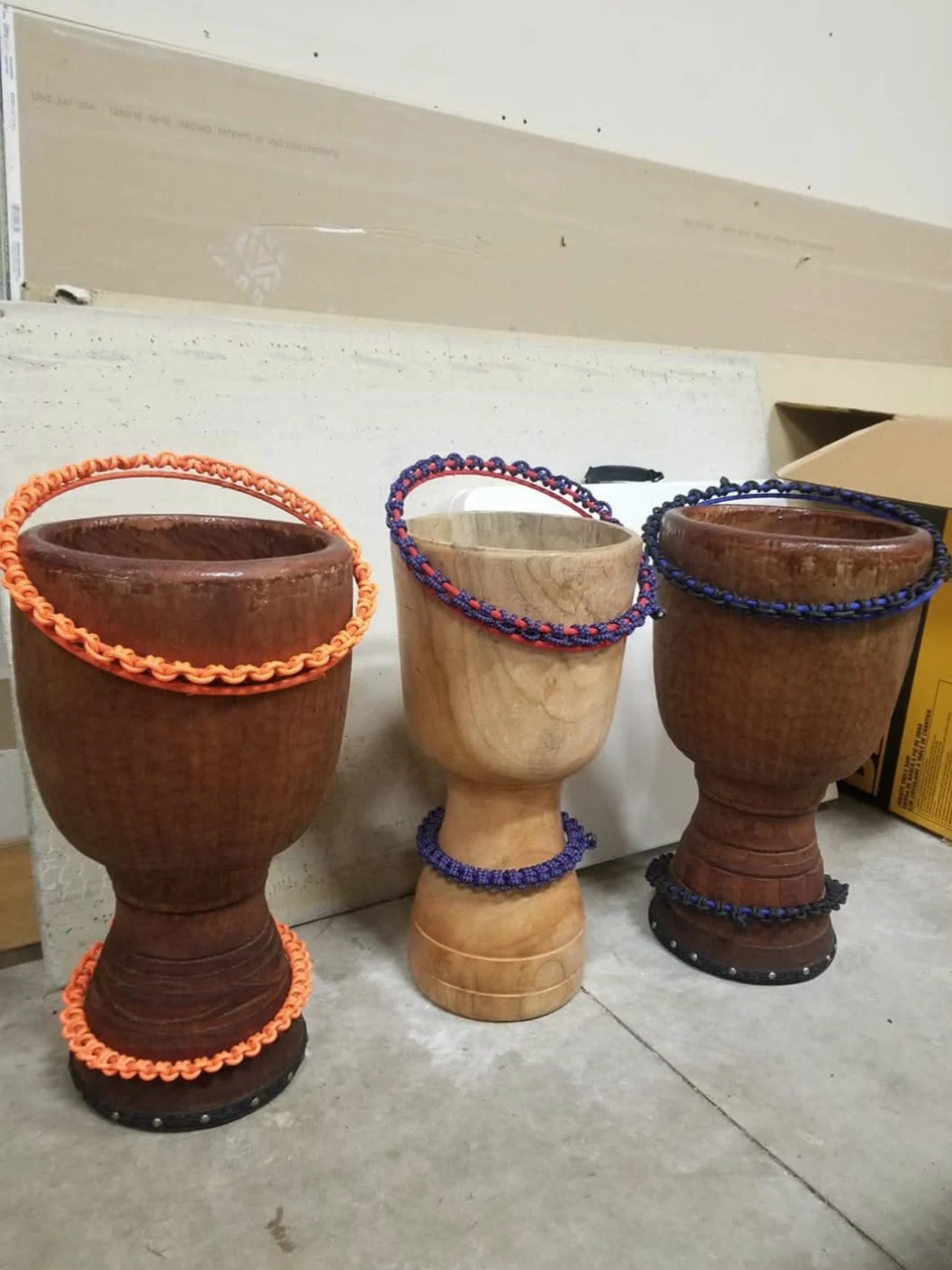 Open wooden djembe shells with colored ropework in progress