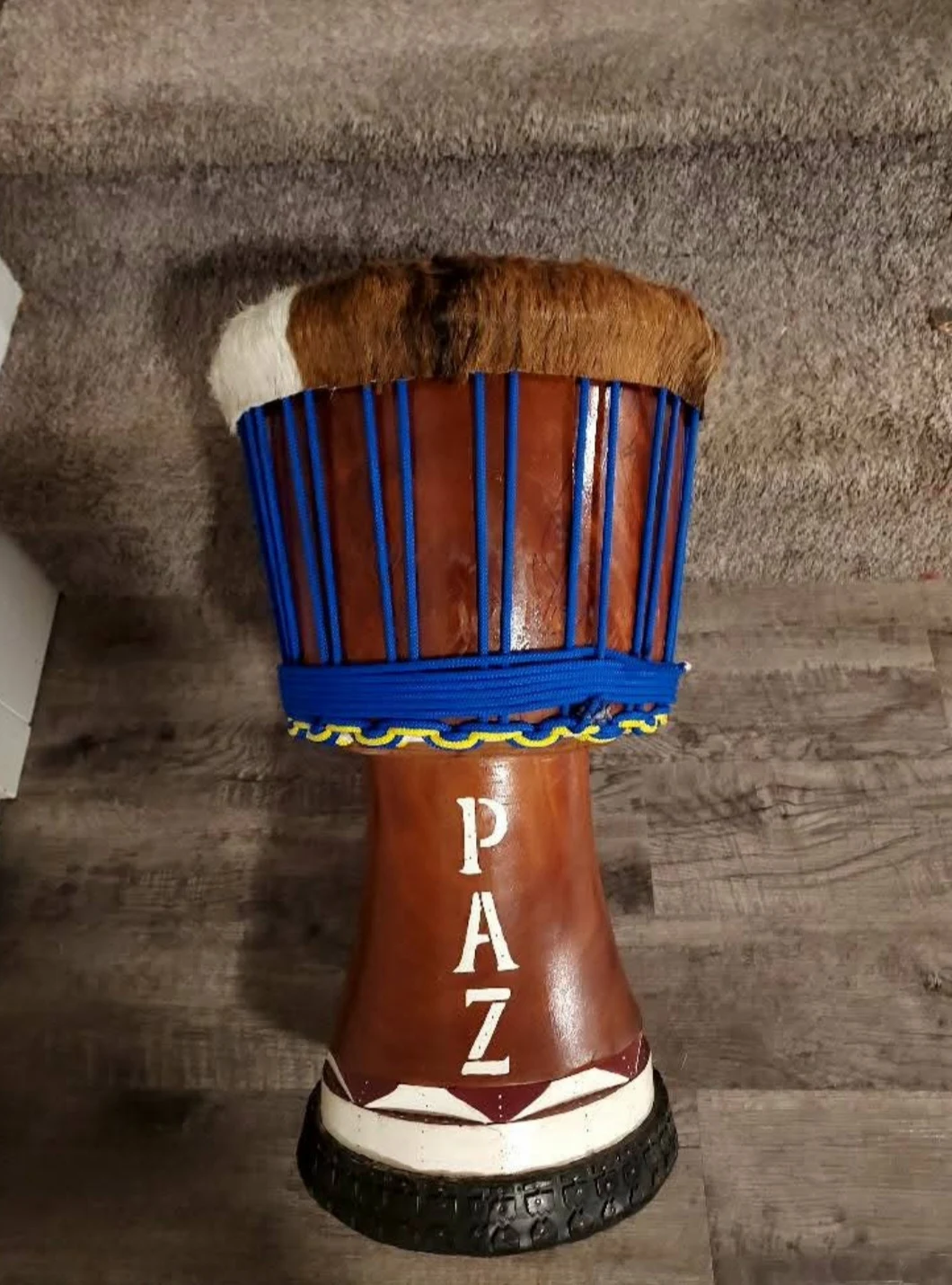 A handmade djembe with blue rope and Justin’s PAZ signature